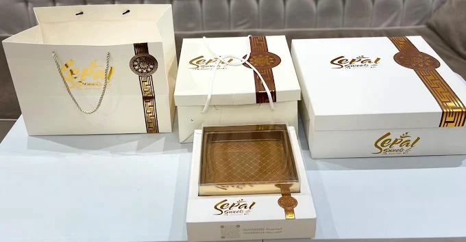 علب مطبوعة باللونين الأبيض والذهبي على طاولة